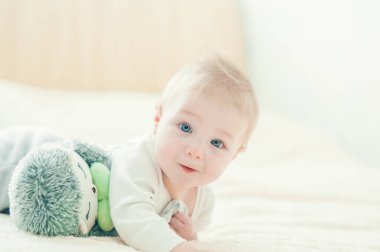 Yakışıklı, neşeli çocuk yatakta emekliyor..