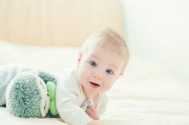 Yakışıklı, neşeli çocuk yatakta emekliyor..