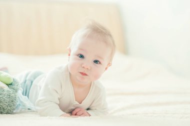 Yakışıklı, neşeli çocuk yatakta emekliyor..