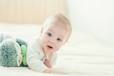 Yakışıklı, neşeli çocuk yatakta emekliyor..