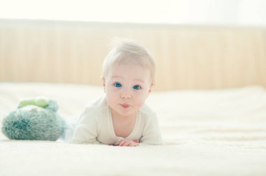 Yakışıklı, neşeli çocuk yatakta emekliyor..