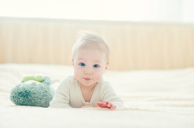 Yakışıklı, neşeli çocuk yatakta emekliyor..