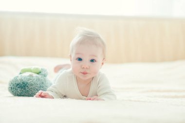 Yakışıklı, neşeli çocuk yatakta emekliyor..