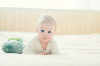 Yakışıklı, neşeli çocuk yatakta emekliyor..