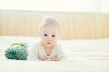 Yakışıklı, neşeli çocuk yatakta emekliyor..