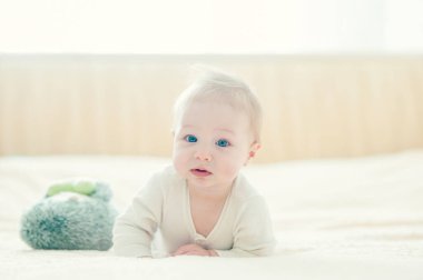 Yakışıklı, neşeli çocuk yatakta emekliyor..