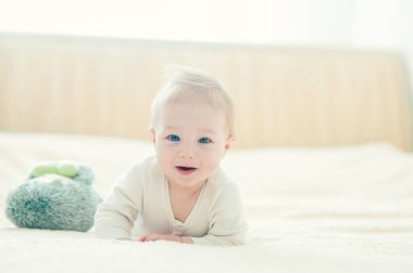 Yakışıklı, neşeli çocuk yatakta emekliyor..