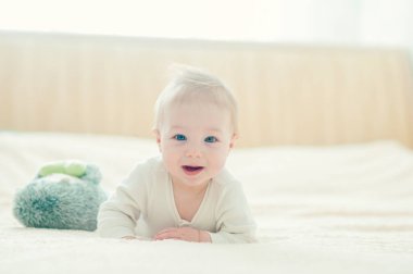 Yakışıklı, neşeli çocuk yatakta emekliyor..