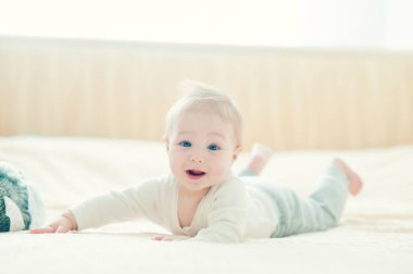 Yakışıklı, neşeli çocuk yatakta emekliyor..