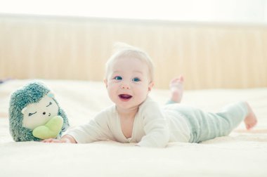 Yakışıklı, neşeli çocuk yatakta emekliyor..