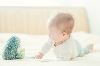 Yakışıklı, neşeli çocuk yatakta emekliyor..