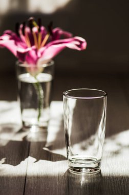 Ahşap zemine yerleştirilmiş cam soğuk su. Zambak çiçekleri..