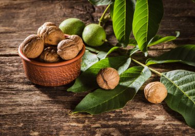 bowl with fresh walnuts, leaves and nut shell on gray stone background. Autumn seasonal.