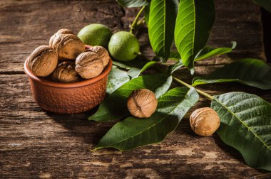 bowl with fresh walnuts, leaves and nut shell on gray stone background. Autumn seasonal.