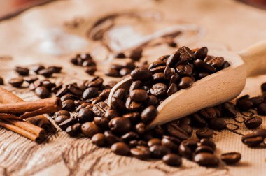 Kahve çekirdeklerine yakın çekim. Kahve çekirdekleri ahşap masada. Kahve dokusunun arka planında. Kahve çekirdekleri masaya saçılmış..