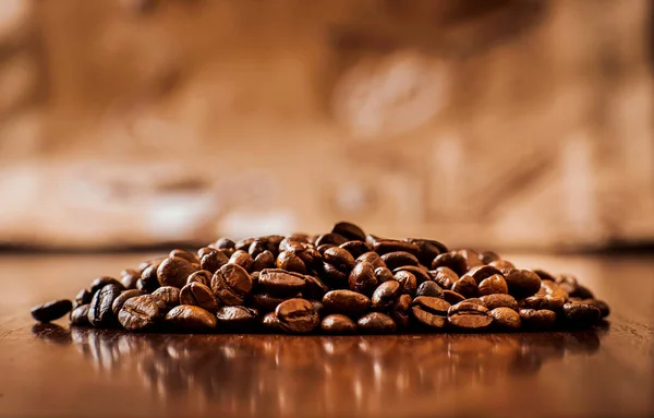 Cup of coffee, bag and scoop.coffee beans on wooden table. Background of ground coffee texture. Coffee beans are scattered on the table.Packaging for coffee