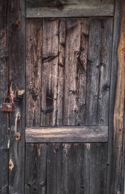 Paslı asma kilidi olan eski, boyanmamış ahşap kapı. doku