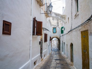 İtalya 'nın güneyindeki antik Ostuni, Apulia bölgesinde geleneksel beyaz evleri olan Picturesque kaldırım taşı sokağı.