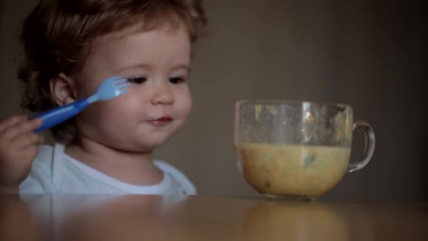 Маленька кучерява дитина їсть апетитні овочі з жорсткою виделкою — стокове відео