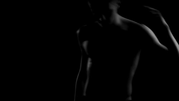attrayant gars avec un torse nu beau se déplace son corps dans l'obscurité 