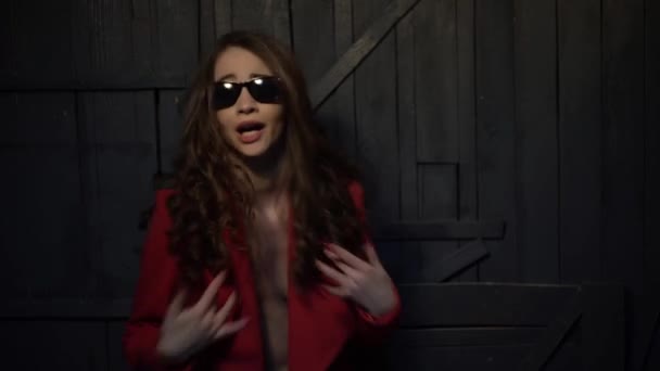 Sexy brunette woman in sunglasses and a red jacket on a naked body sings rap — Stock Video