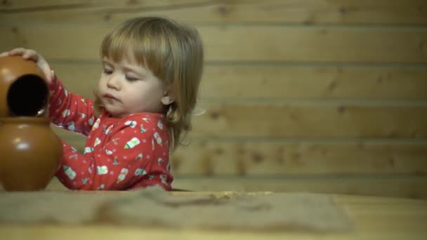 Criança encaracolado bonito brincando na cozinha com jarros, derramando água e bebidas — Vídeo de Stock