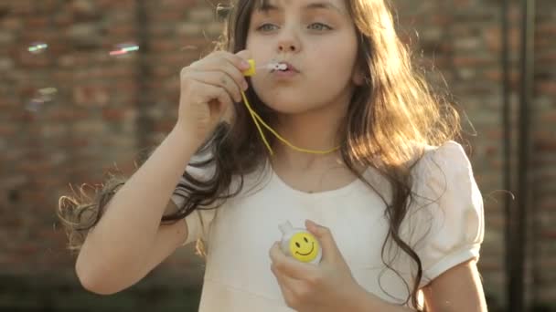 Portrait de drôle belle petite fille soufflant des bulles de savon — Video