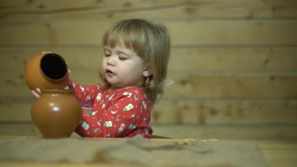 Beautiful curly-haired child in the kitchen in the cottage playing with utensils and drinking water — Stock Video