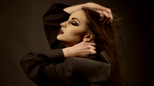 Hermosa chica con maquillaje oscuro tocando su cabello en el viento en el estudio — Vídeos de Stock