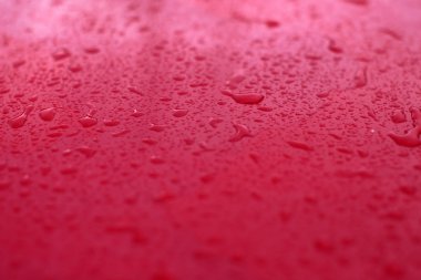 Kırmızı zemin üzerine yağmur damlaları