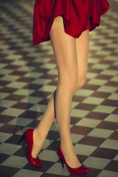 Patas femeninas en falda roja y zapatos — Foto de Stock