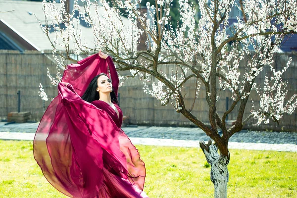 Kobieta w czerwonej sukience w pobliżu kwitnąć — Zdjęcie stockowe