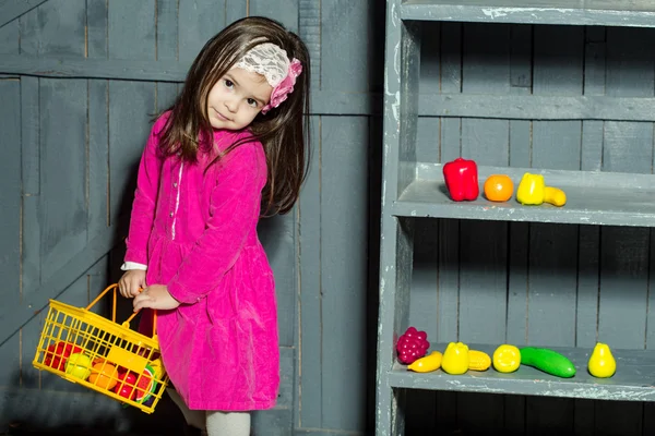 Little girl with plastic fruits and vegetables — Stock Photo, Image