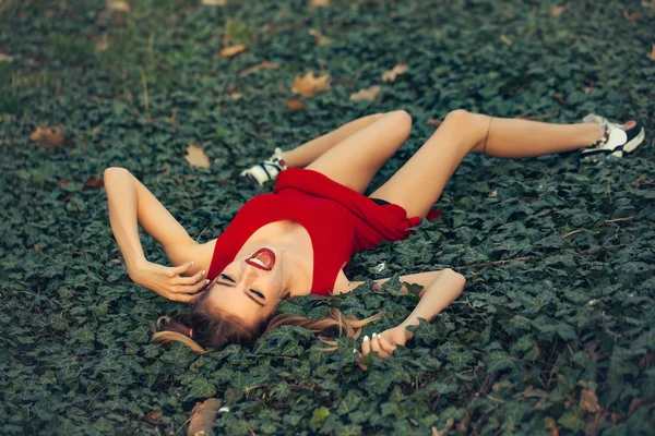 Gülümseyen kız yeşil yapraklarda yalan