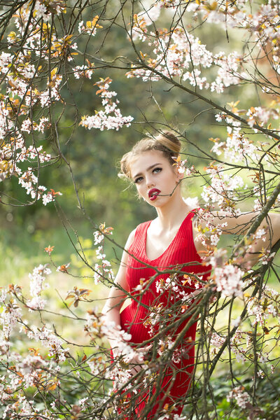 Beautiful sensual young woman enjoying beauty in a flowering spring garden