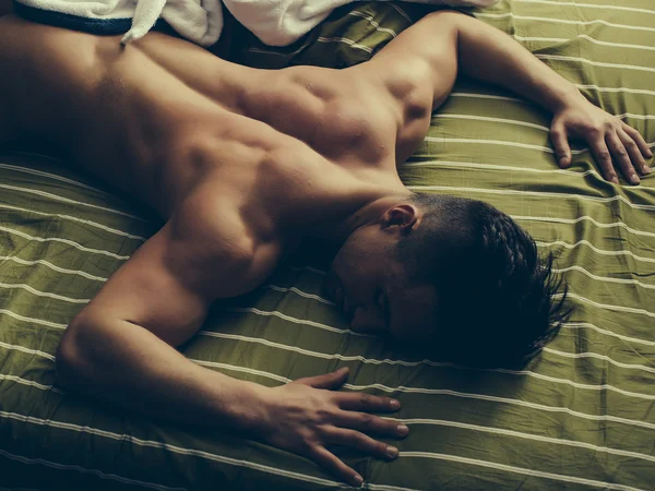 Muskulöser Mann im Bett — Stockfoto