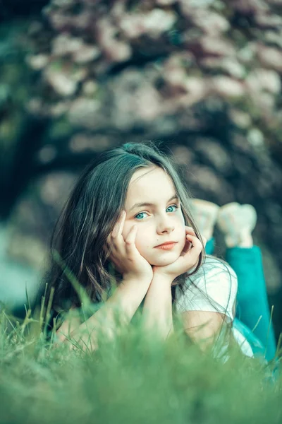 Liten flicka på gräs i blom — Stockfoto