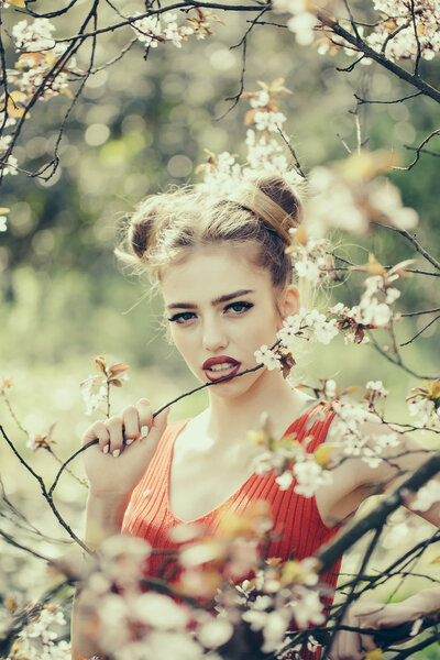 Beautiful sensual young woman enjoying beauty in a flowering spring garden