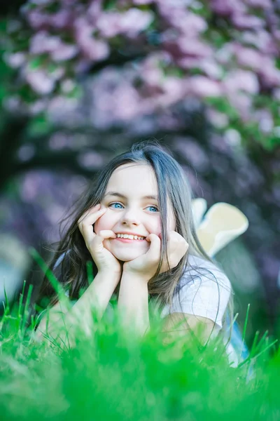 Kleines Mädchen auf blühendem Gras — Stockfoto