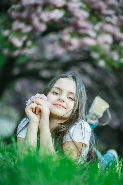 Kleines Mädchen auf blühendem Gras — Stockfoto