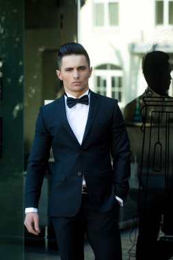 Cam kapı yakınındaki elbiseli genç adam