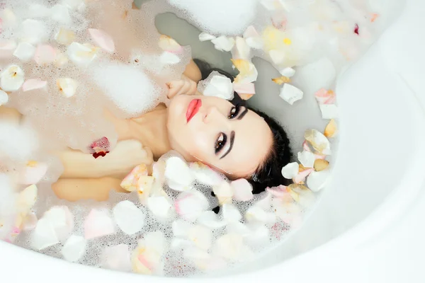 Mulher sexy no banho com pétalas — Fotografia de Stock