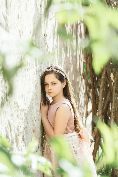 Όμορφο κορίτσι κοντά σε λευκό τοίχο στα φύλλα — Φωτογραφία Αρχείου