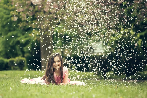 Niña sobre hierba verde con pétalos —  Fotos de Stock