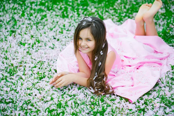 Menina na grama verde com pétalas — Fotografia de Stock