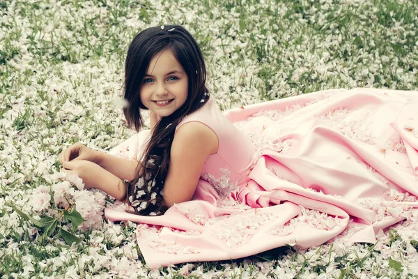 Bambina su erba verde con petali — Foto Stock