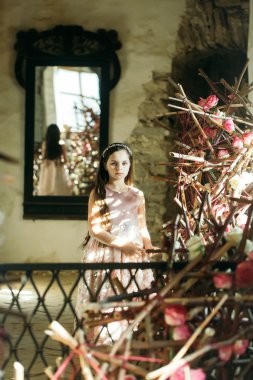 Ayna ve pembe çiçekler yakınındaki küçük kız