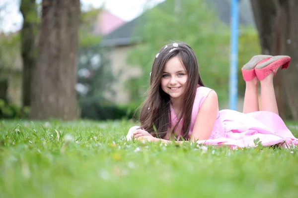 Petite fille sur herbe verte avec des pétales — Photo