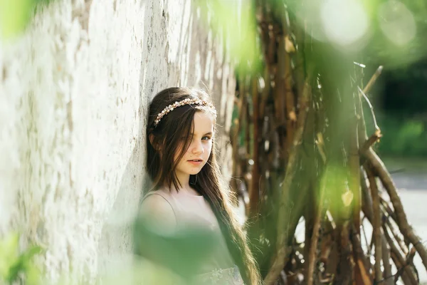 Pretty girl near white wall in leaves — Stock Photo, Image