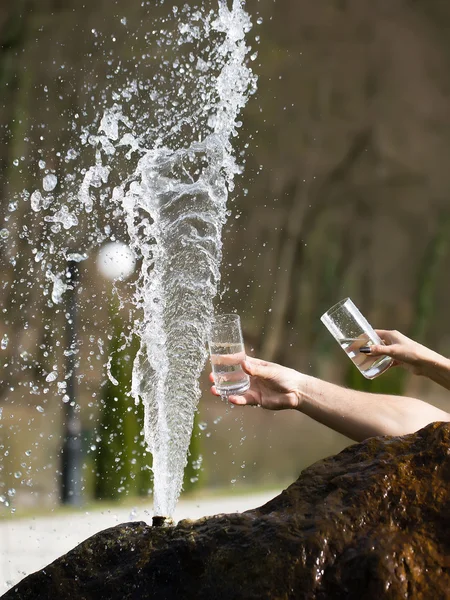 Human hands with glass near fountain